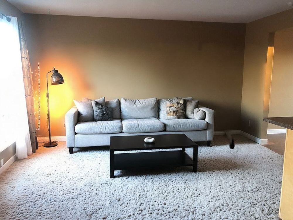 Dasselbe Wohnzimmer mit Sofa, Couchtisch und Stehlampe