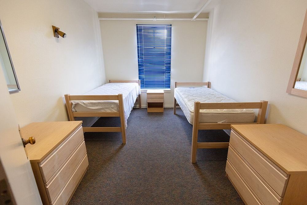 Schlichtes Zimmer mit zwei Einzelbetten, Kommoden und Fenster